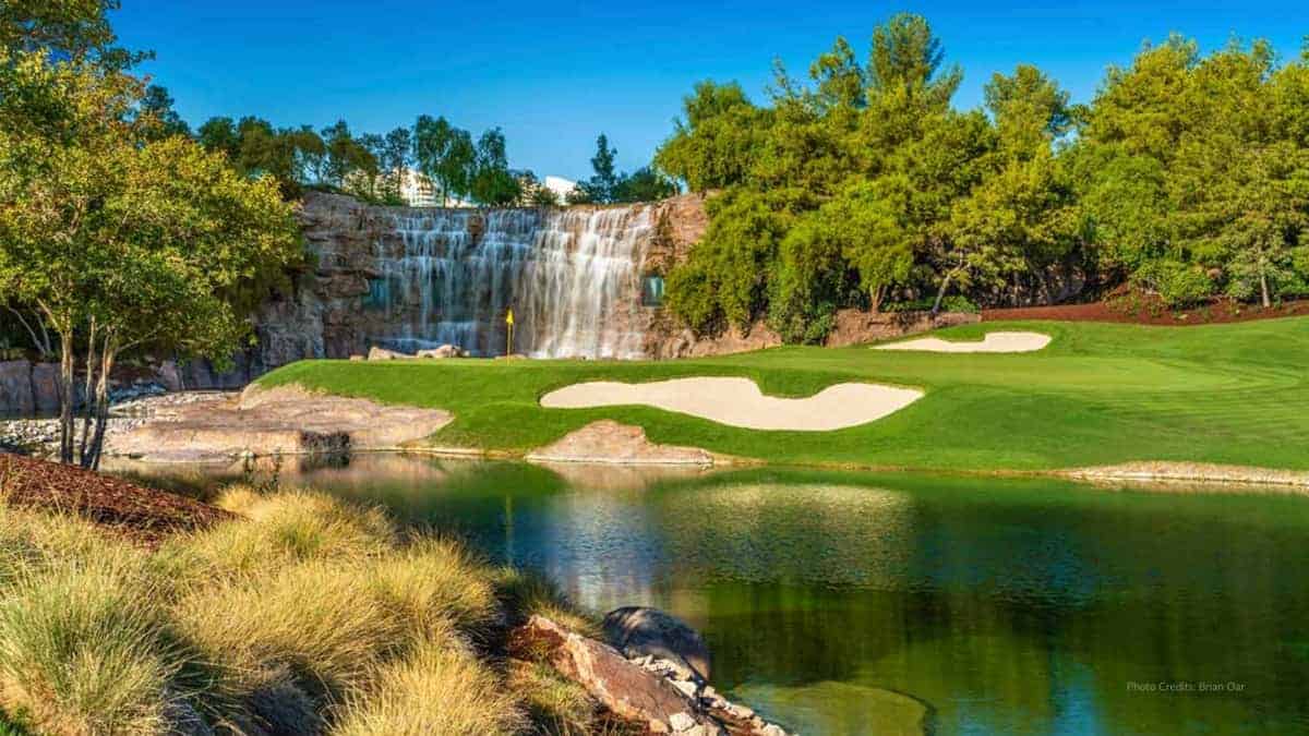 a golf course with a waterfall in the background
