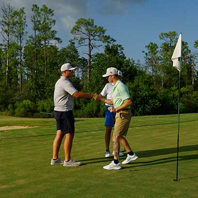 two men shaking hands on a golf course