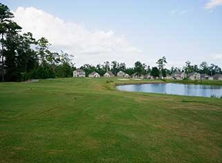 a golf course with water and houses in the background