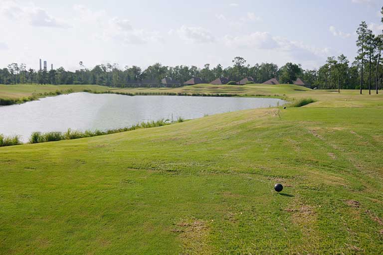 a golf course with a lake and trees in the background