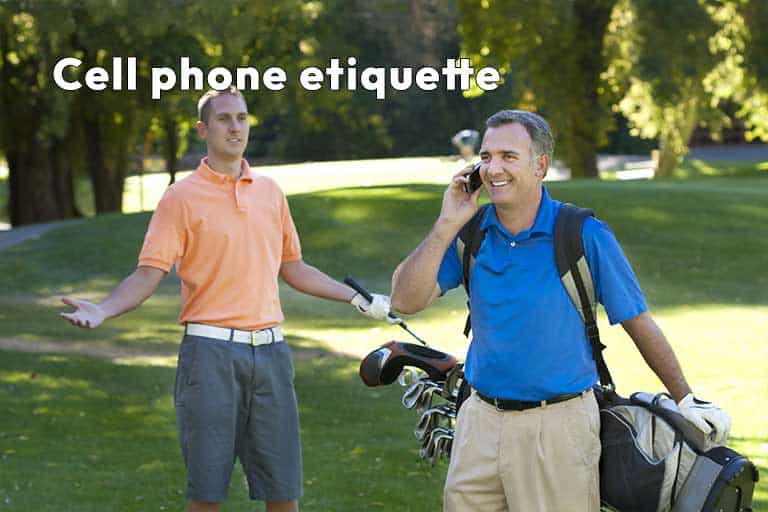 Two men on a golf course with one speaking on a cell phone while the other looks on, gesturing. Cell phone etiquette