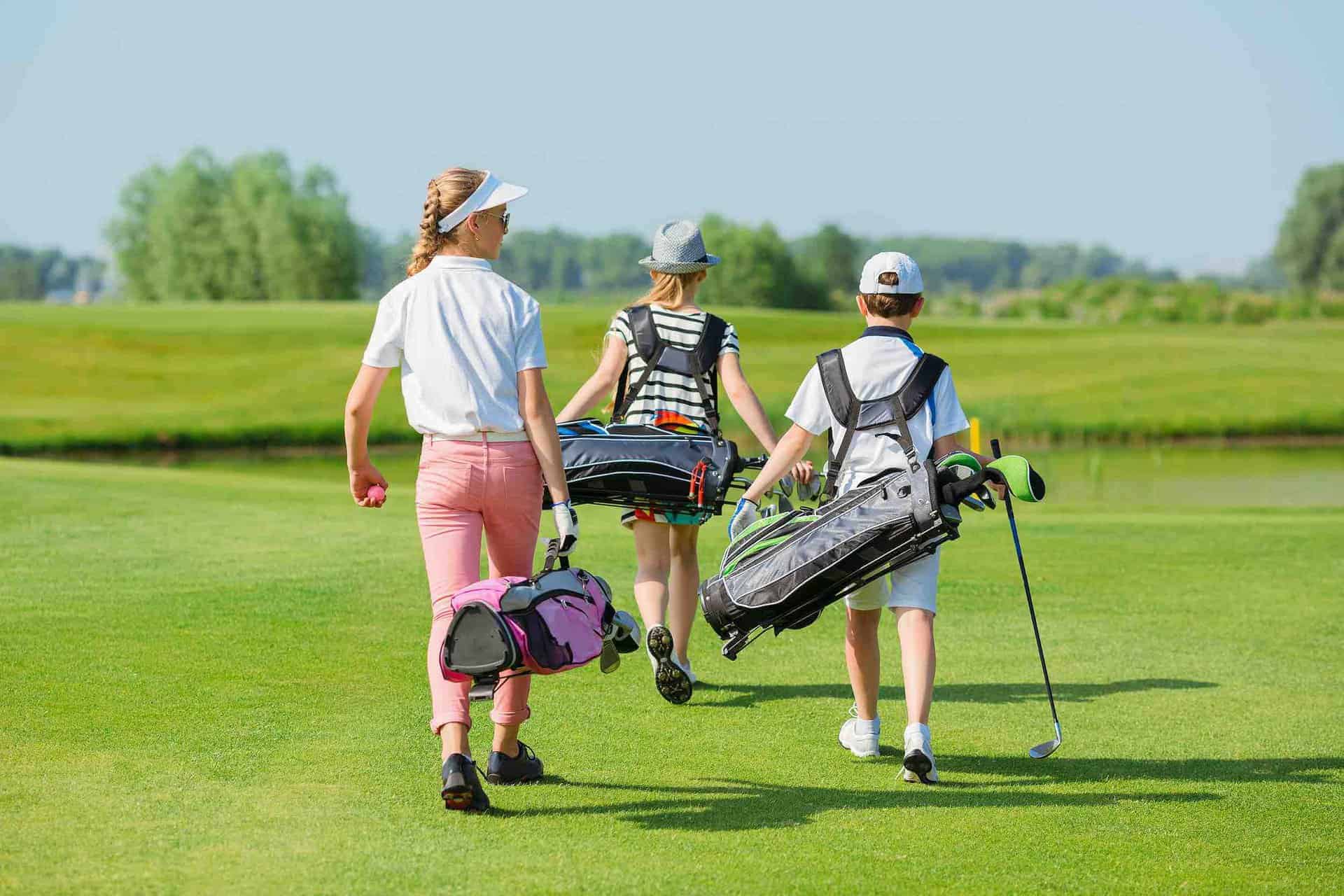 three people walking on a golf course with luggage