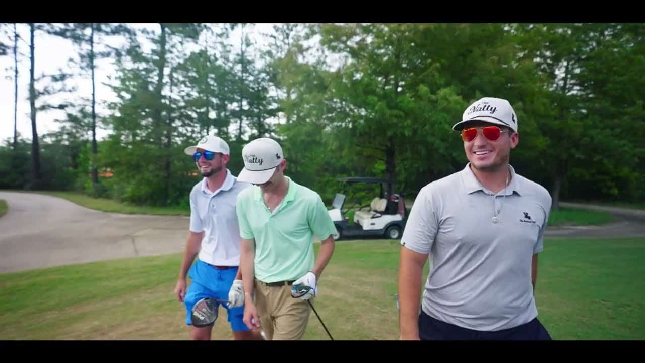 three men standing next to each other on The National Golf Club of Louisiana golf course